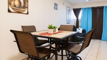 A dining area with a table, chairs, and a potted plant.