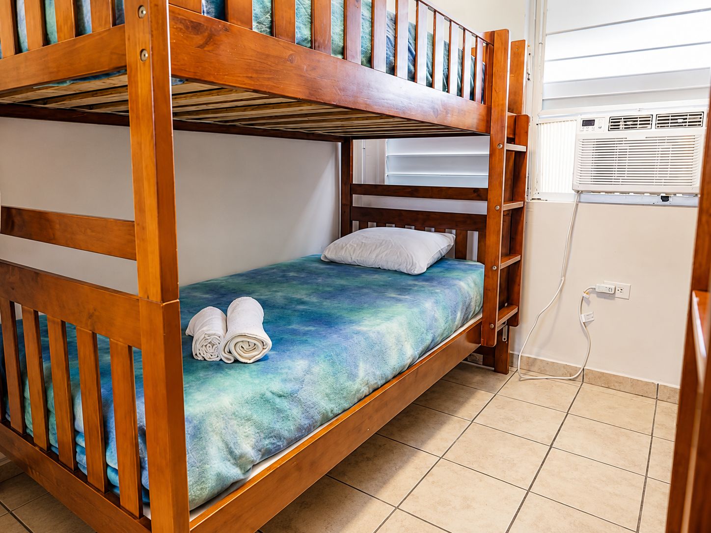A bunk bed with a blue mattress, a white pillow, and two rolled towels.