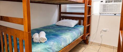 Uma cama beliche com colchão azul, travesseiro branco e duas toalhas enroladas.