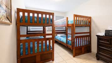 Une chambre avec des lits superposés, une commode et un tableau encadré accroché au mur.