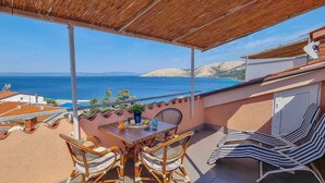 Una terrazza con tavolo e sedie affacciata su una vista costiera.