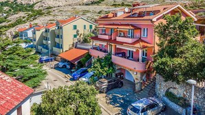 Un edificio residenziale a più piani con balconi, un'area di parcheggio e montagne sullo sfondo.