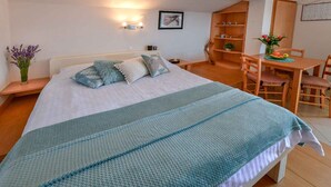 Una camera da letto ordinata con un letto, comodini, un tavolino con un vaso di fiori e una sedia di legno.