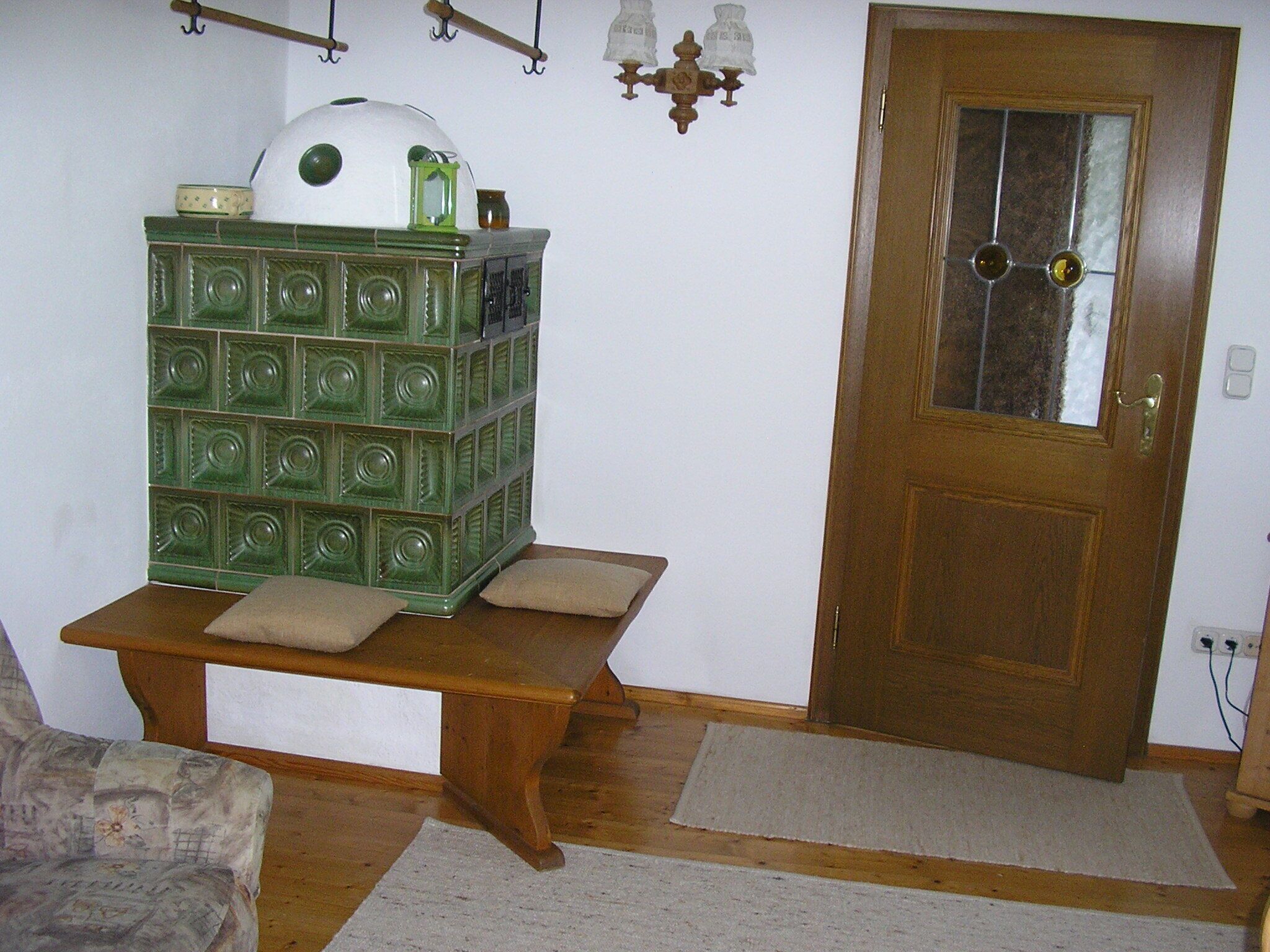 A room with a wooden bench, a green storage unit, a door with a glass panel, and a chandelier.