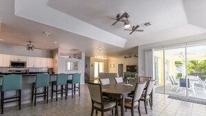 A spacious kitchen with modern appliances, a dining area with a large table and chairs, and a sliding glass door leading to an outdoor patio. - Exclusive Villa Fantastic Lakeview, Pool & Spa, Breathtaking Sunset (Cape Coral)