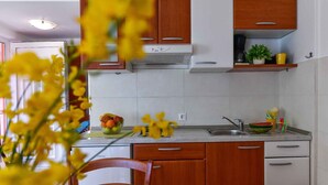 Une cuisine avec des meubles de rangement en bois, un évier en acier inoxydable et un panier de fruits posé sur le plan de travail.
