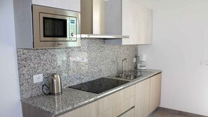 A kitchen with granite countertops, a stainless steel sink, a microwave, and wooden cabinets.