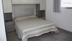 A bedroom with a bed, nightstands, and built-in storage cabinets.