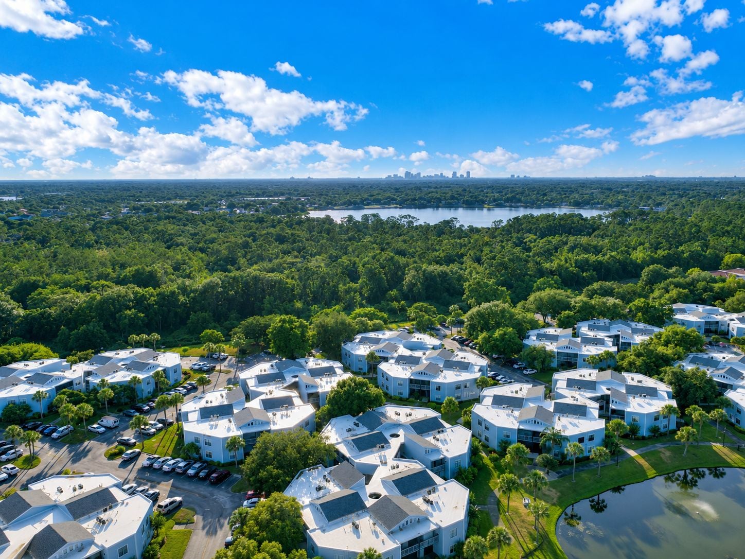 A residential area with multiple two-story buildings, a parking lot, and a lake in the background.