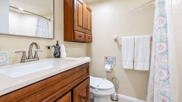 A bathroom with a wooden vanity, a sink, a toilet, and a shower curtain.