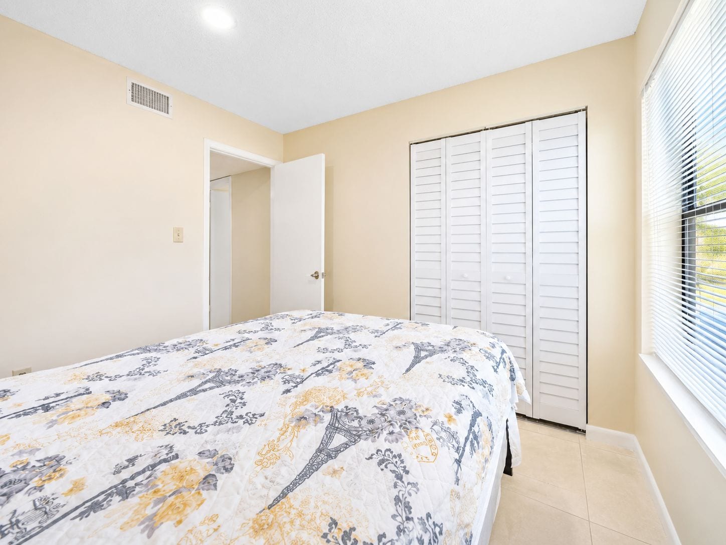 A bedroom with a bed, a closet, and a window with blinds.