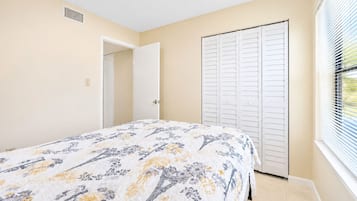 A bedroom with a bed, a closet, and a window with blinds.