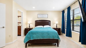A hotel room with a bed, two bedside tables, a nightstand, a window with curtains, and a wall sign. - Colinas del Atlantico Vacational House 1st Floor (Isabela)
