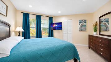 Ein Schlafzimmer mit einem Bett, einem Nachttisch, einem Fernseher, einer Kommode und einem Fenster mit Vorhängen.