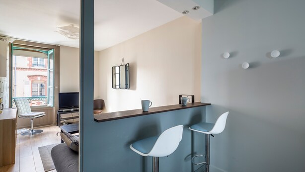 Une cuisine moderne avec un coin bar, une table à manger et un téléviseur.