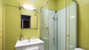 Une salle de bain avec une douche à parois de verre, un lavabo blanc et un miroir au-dessus.