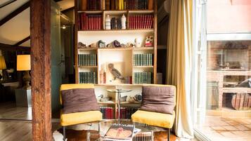 A cozy reading nook with two armchairs, a glass coffee table, and a bookshelf filled with books and decorative items.