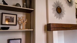 A room with a wooden shelf displaying a framed photograph, a wooden tree sculpture, and a framed Wi-Fi connection sign.