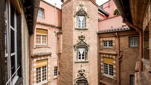 A narrow alleyway with traditional brick buildings, featuring ornate window frames and shutters.