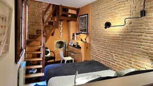 Een compacte slaapkamer met een entresol als werkruimte, een bed, een bureau en een stoel.