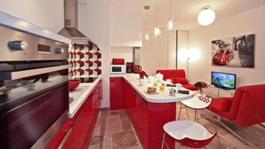 Eine moderne Küche mit Einbauofen, Kaffeemaschine und einem Essbereich mit roten Stühlen und einem weißen Tisch.