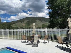 Relax by the pool surrounded by lush greenery and a serene natural landscape.