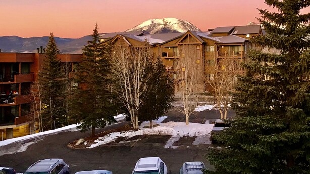 A lodge with multiple buildings, a parking lot, and a mountain in the background. - Central location to Keystone, Breckenridge and Copper Mtn.  (Dillon)
