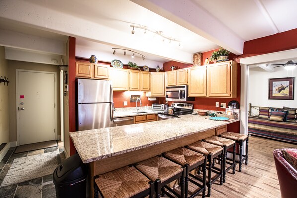Enjoy cooking in this well-equipped kitchen with a large island and bar stools, featuring a refrigerator, microwave, and oven.