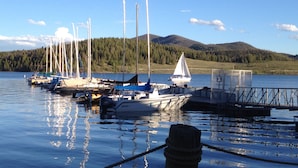 A marina with boats docked, a sailboat in the water, and a forested hill in the background. - Central location to Keystone, Breckenridge and Copper Mtn.  (Dillon)
