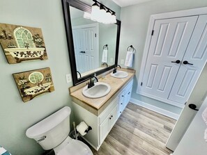 A bathroom with a toilet, two sinks, a mirror, and a door.