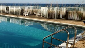 Ein Pool mit Metallgeländer, weißen Stühlen und Blick auf das Meer.
