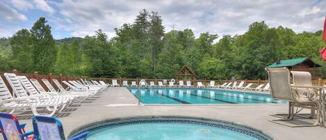 A swimming pool area with lounge chairs and a small deck.