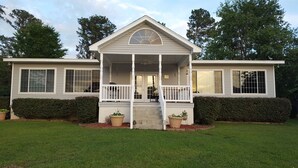 A two-story house with a front porch, large windows, and a small garden area.