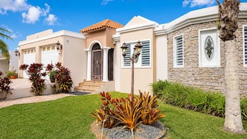 A residential property with a well-maintained lawn, a stone facade, and a traditional entrance with steps.