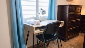 Un pequeño espacio de trabajo con escritorio, silla y un aparador de madera oscura.