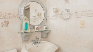 Un baño con un espejo redondo, un lavabo y azulejos decorativos.