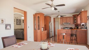 A kitchen with wooden cabinets, a dining table with placemats, and a ceiling fan. - Big vacational house in Isabela (Moca)