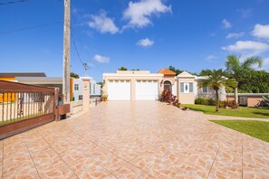 A residential property with a paved driveway, two garage doors, and a well-maintained lawn. - Big vacational house in Isabela (Moca)