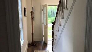 A hallway with a patterned rug, a coat rack, and a staircase leading to a garden. - Port Clyde Village House   -   Summer of 2026 is booked. See you in 2027 (St George)