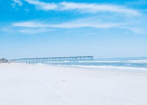 Ein Strand mit einem Steg, der sich ins Meer erstreckt.