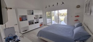 Un dormitorio con cama, armario y puerta corredera de vidrio que da a un espacio exterior.