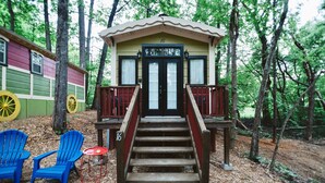 Une cabane en bois avec une porte noire et le numéro « 16 » au-dessus, entourée d’arbres.
