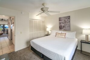 Quarto com cama, ventoinha no teto, luminárias de cabeceira, pintura de Buda e porta que dá para uma varanda.