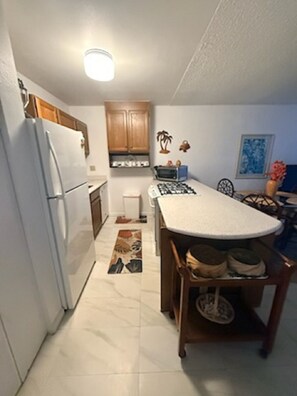 Cocina compacta con refrigerador, microondas, estufa y armarios de madera.