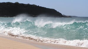 A beach with waves crashing onto the shore and a rocky cliff in the background. - ALOHA OceanFront Condo w.A/C,  Molokai, Hawaii Watch whales Dec-April. (Kaunakakai)