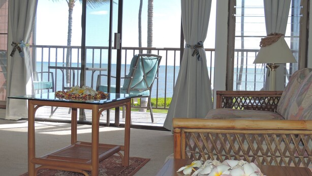 A room with a glass table, a sofa, and a view of the ocean. - ALOHA OceanFront Condo w.A/C,  Molokai, Hawaii Watch whales Dec-April. (Kaunakakai)