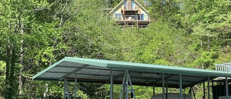 A lakeside cabin with a covered dock and a boat.