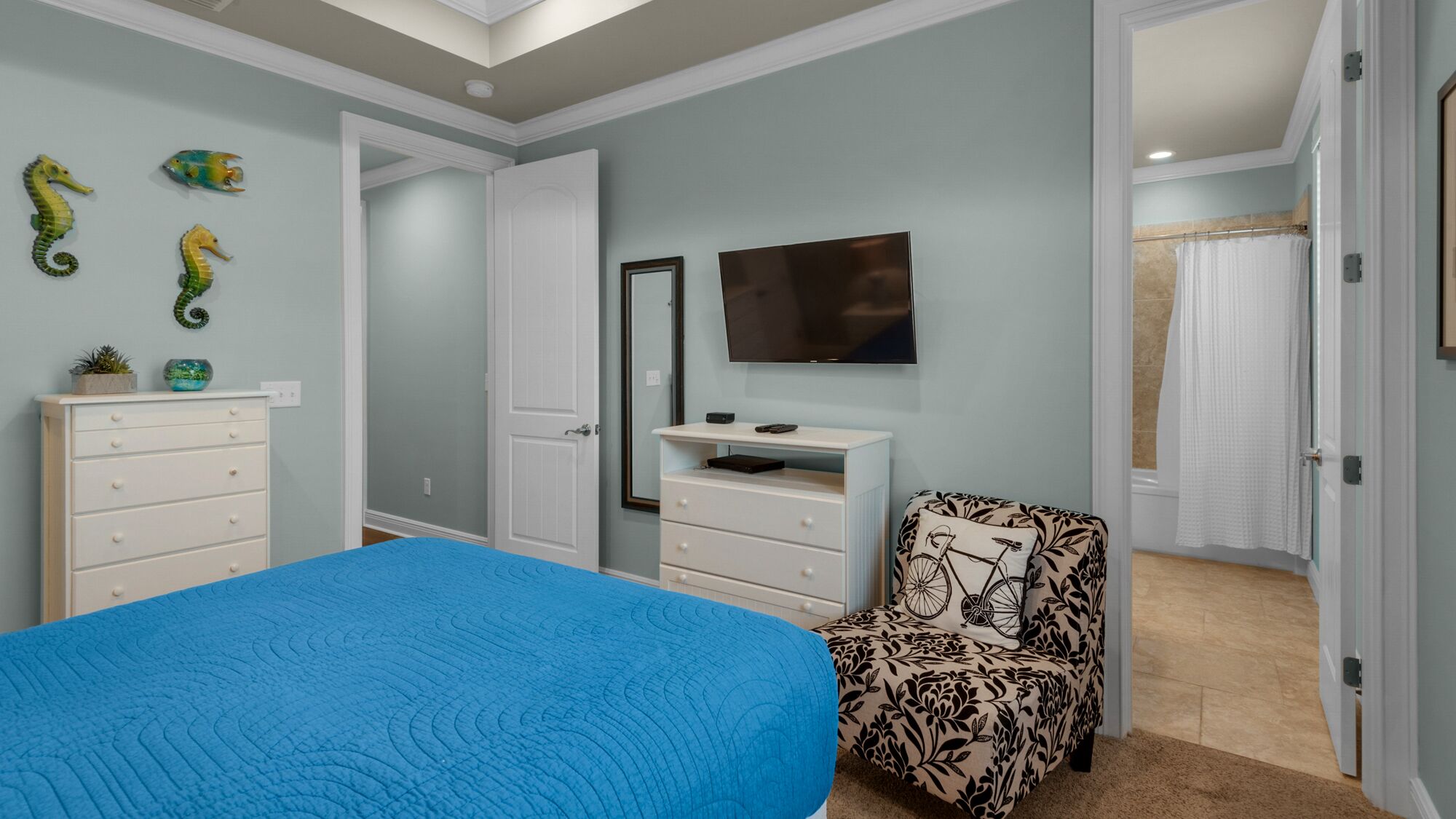 Une chambre à coucher avec un lit, une télévision, une commode et une chaise.