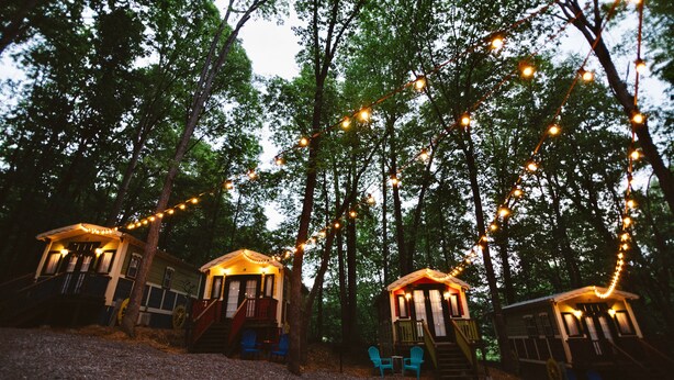 Three treehouse cabins with string lights, surrounded by trees. - #15 Queenie - Gypsy Cottage (Sevierville)