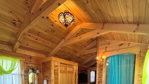 Ein gemütliches Blockhaus-Interieur mit Holzwänden, einem blauen Sofa, einem Holzesstisch und einer Chandelüster.